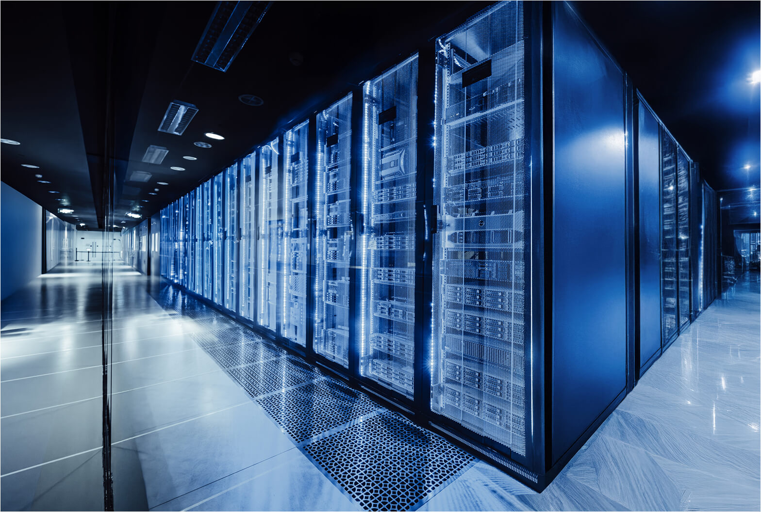Rows of illuminated server racks in a modern blue-lit data center corridor with reflective flooring.