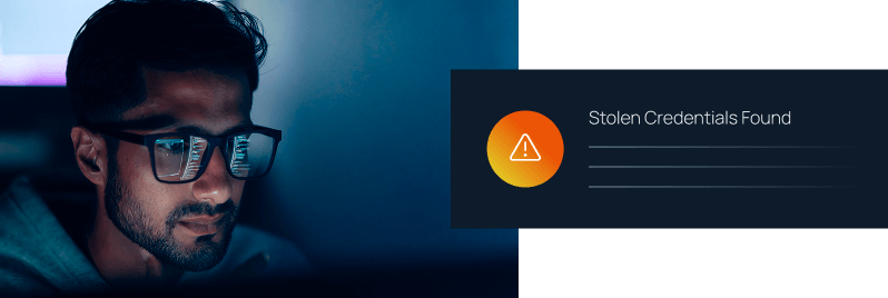 Man wearing glasses staring at a screen in a dark room beside a "Stolen Credentials Found" warning alert notification.