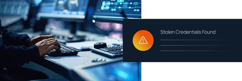 A person typing at a keyboard in a dark monitoring room beside a "Stolen Credentials Found" warning alert with an orange